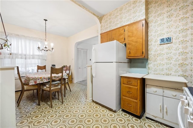 kitchen featuring an inviting chandelier, white appliances, and hanging light fixtures