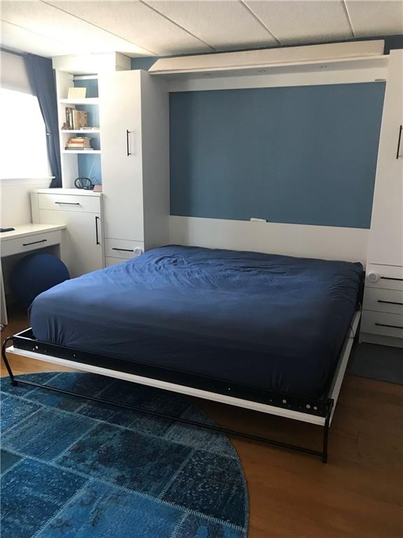 bedroom with a drop ceiling and wood finished floors