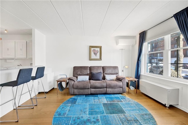 living area with light wood-type flooring, baseboards, and a wall mounted AC