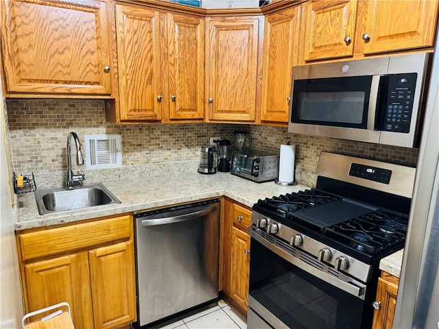 kitchen with sink, backsplash, light tile patterned flooring, and appliances with stainless steel finishes