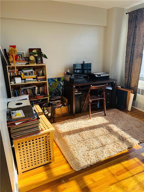 office area with hardwood / wood-style flooring and radiator heating unit