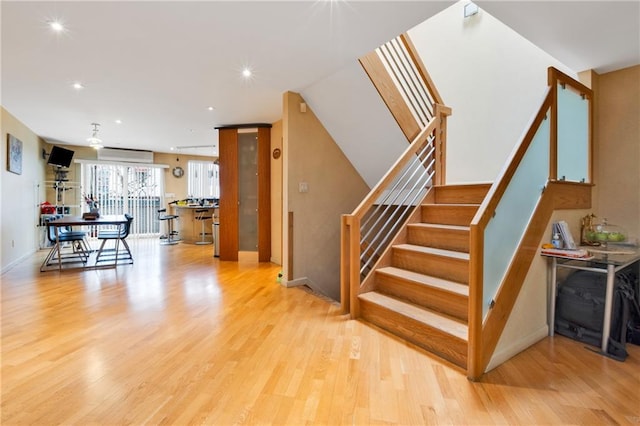 staircase featuring recessed lighting, wood finished floors, and a wall mounted air conditioner