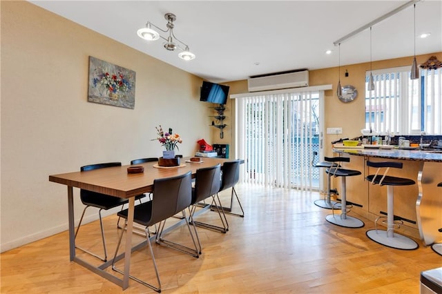 dining area featuring light wood-style floors, baseboards, and a wall mounted AC