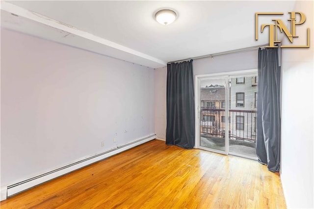 spare room with a baseboard heating unit and wood finished floors