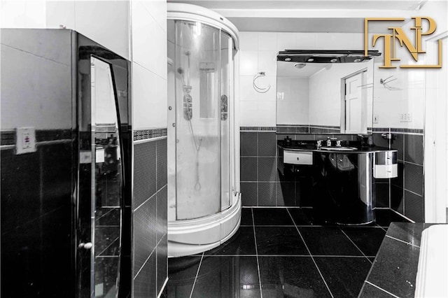 bathroom with vanity, tile walls, a stall shower, and tile patterned flooring