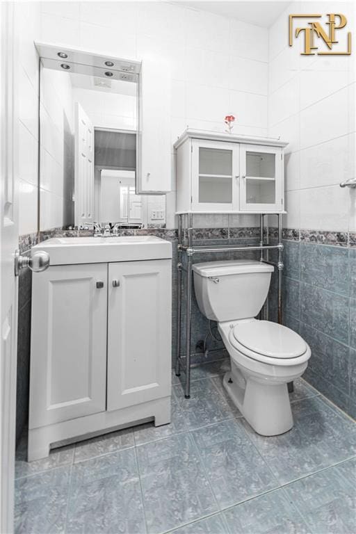 bathroom featuring tile patterned floors, toilet, tile walls, and vanity