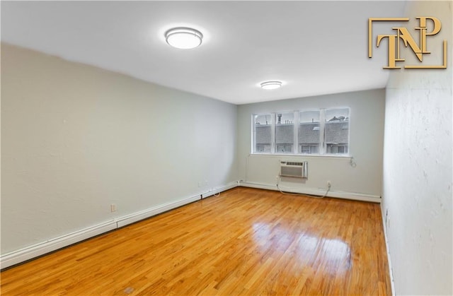 spare room featuring baseboards, an AC wall unit, and wood finished floors