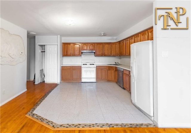 kitchen with white appliances, light countertops, brown cabinets, and under cabinet range hood