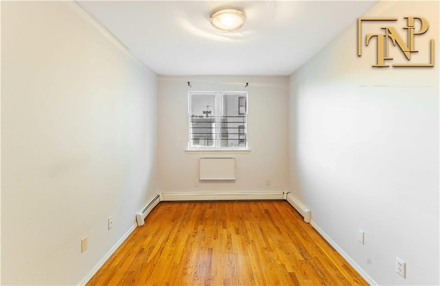 empty room with baseboard heating, a baseboard heating unit, light wood-type flooring, and baseboards