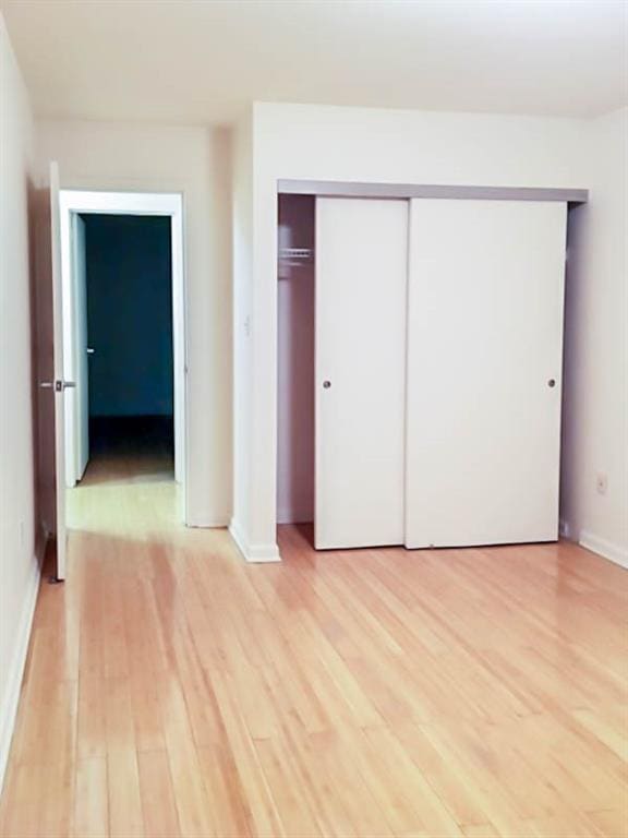 unfurnished bedroom with light wood-type flooring and a closet