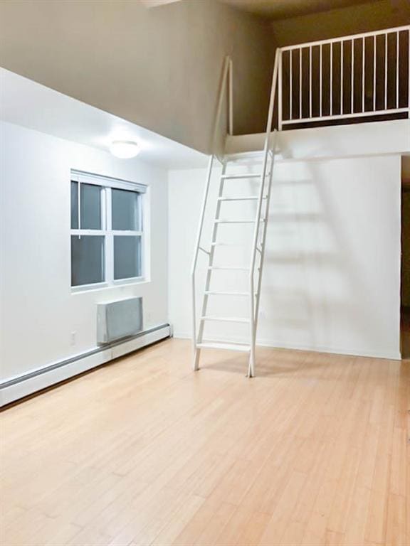 spare room with wood-type flooring and a baseboard heating unit