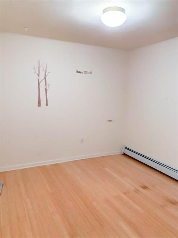 unfurnished room with a baseboard radiator and light wood-type flooring