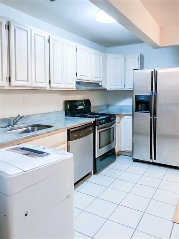 kitchen featuring washer / clothes dryer, white cabinetry, sink, light tile patterned floors, and stainless steel appliances