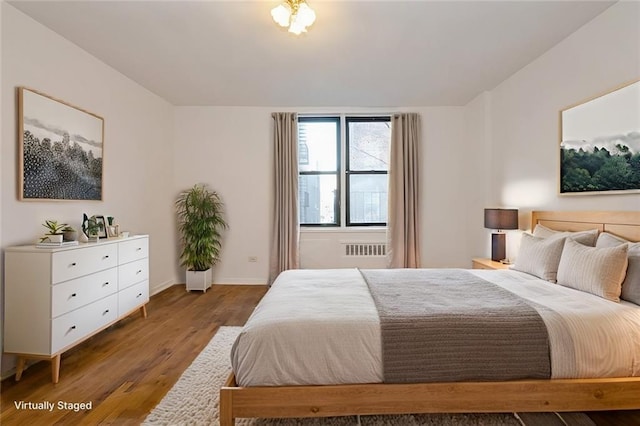 bedroom with baseboards, wood finished floors, and radiator