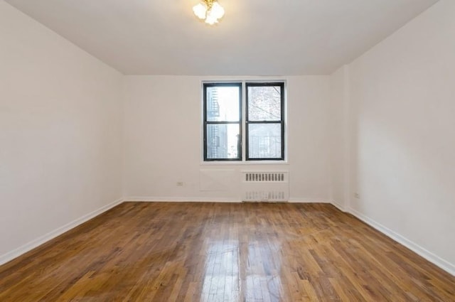 spare room with radiator, baseboards, and hardwood / wood-style floors