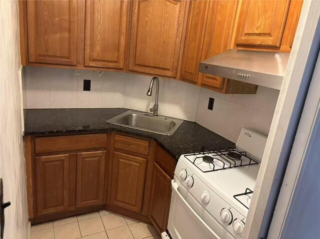 kitchen featuring sink, dark stone countertops, range hood, tasteful backsplash, and white gas stove