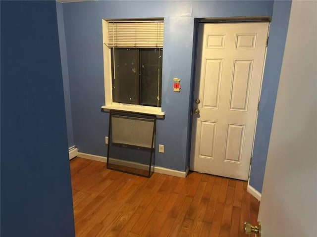 empty room with baseboard heating and light hardwood / wood-style floors