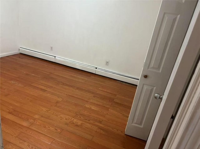 empty room featuring a baseboard radiator and hardwood / wood-style floors