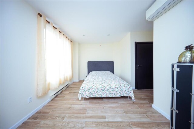 bedroom with a wall unit AC and a baseboard heating unit