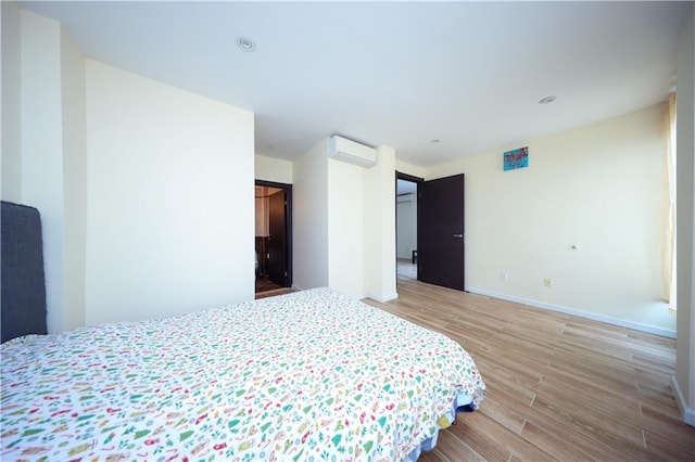 bedroom with hardwood / wood-style flooring and a wall mounted AC