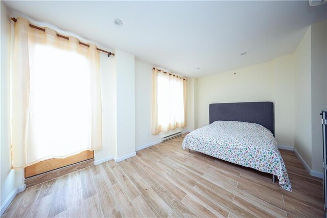 bedroom with a baseboard radiator and light hardwood / wood-style floors