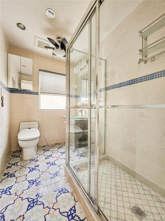 full bathroom with tile walls, toilet, a stall shower, ceiling fan, and tile patterned flooring