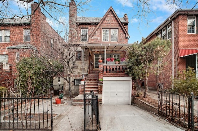 tudor house featuring an attached garage, brick siding, fence, driveway, and stairway