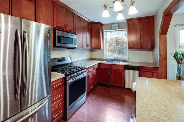 kitchen with backsplash, dark wood-style flooring, stainless steel appliances, and a sink