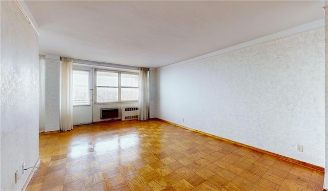 spare room featuring light parquet flooring, radiator, and a fireplace