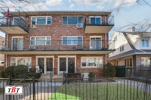 townhome / multi-family property featuring a fenced front yard, brick siding, and french doors