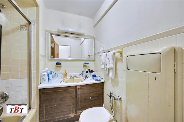 bathroom with bath / shower combo with glass door, toilet, tile walls, and vanity