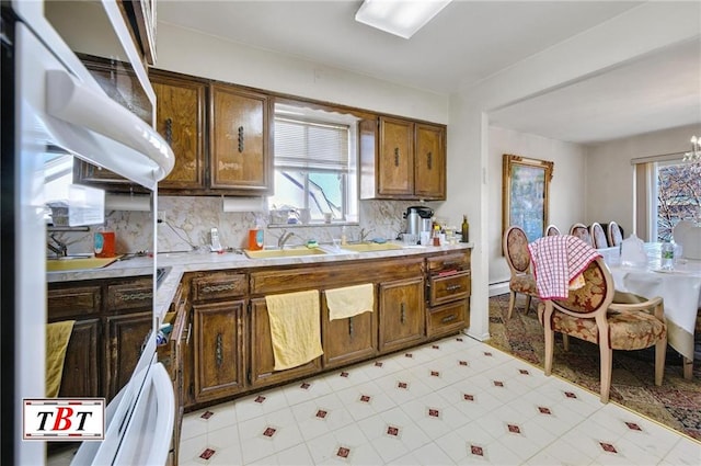 kitchen with an inviting chandelier, backsplash, and sink