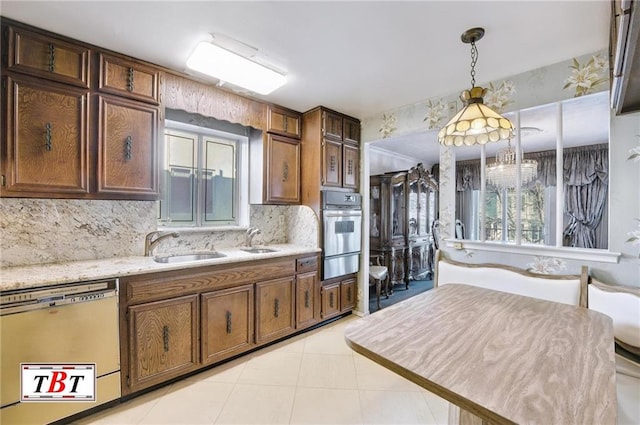 kitchen with pendant lighting, sink, oven, white dishwasher, and light stone countertops