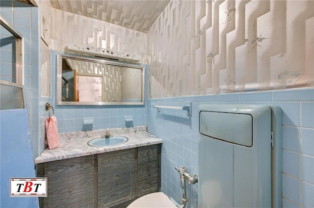 bathroom featuring a wainscoted wall, toilet, tile walls, and vanity