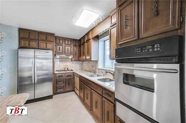 kitchen featuring light tile patterned floors, sink, dark brown cabinets, stainless steel appliances, and decorative backsplash