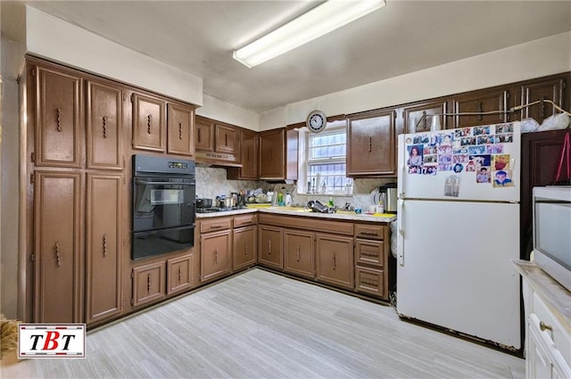 kitchen with white fridge, oven, light hardwood / wood-style floors, and gas cooktop