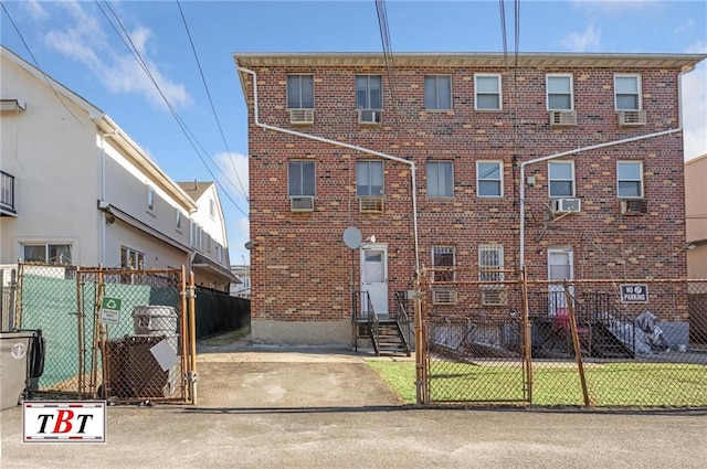 view of front of house with cooling unit, brick siding, and fence