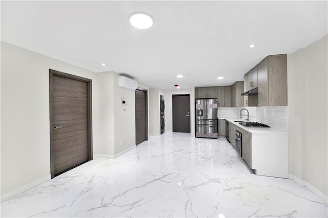 kitchen with a wall unit AC, stainless steel appliances, marble finish floor, light countertops, and backsplash