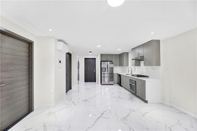 kitchen with light countertops, gray cabinetry, a wall mounted AC, appliances with stainless steel finishes, and a sink