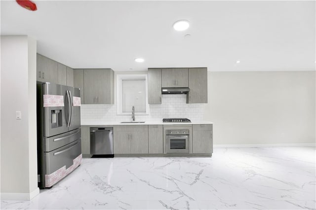 kitchen featuring marble finish floor, stainless steel appliances, decorative backsplash, a sink, and under cabinet range hood