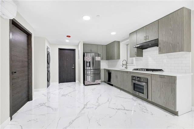 kitchen with stacked washer and dryer, appliances with stainless steel finishes, marble finish floor, gray cabinetry, and under cabinet range hood