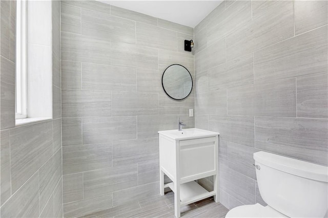 bathroom featuring vanity, toilet, and tile walls