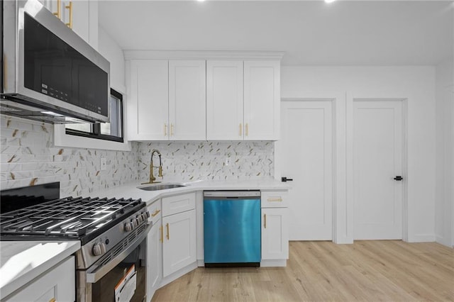 kitchen with sink, white cabinetry, tasteful backsplash, light wood-type flooring, and stainless steel appliances