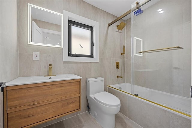 full bath with toilet, tile walls, vanity, tiled shower / bath, and tile patterned floors