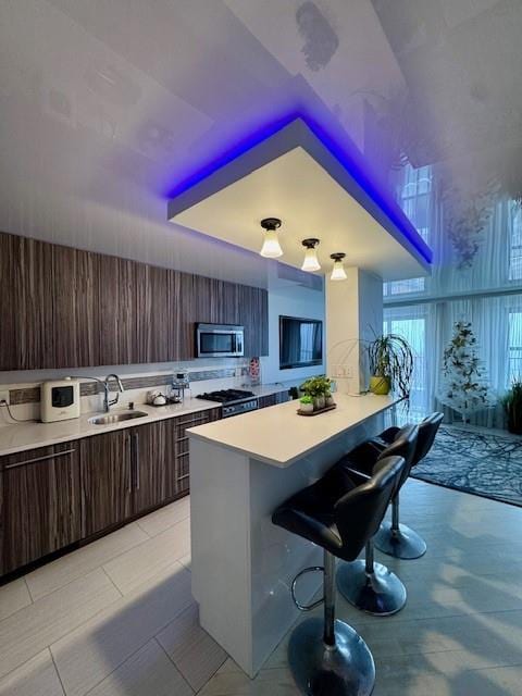 501 Surf Ave Unit 23B, Brooklyn, NY 11224 - kitchen with light countertops, a kitchen breakfast bar, stainless steel microwave, and a sink