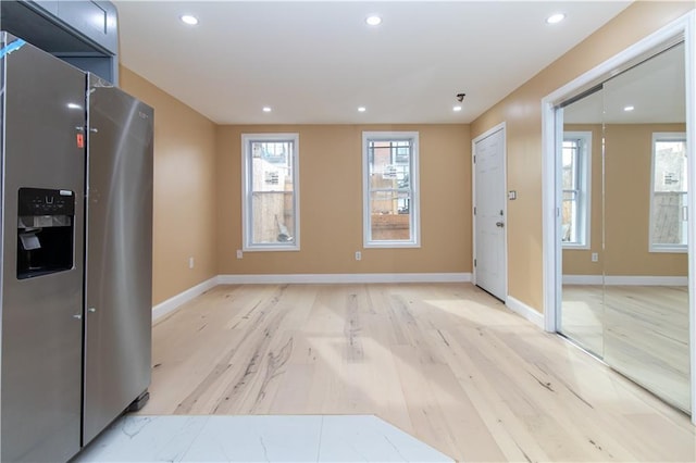 interior space with light wood-style floors, recessed lighting, stainless steel refrigerator with ice dispenser, and baseboards