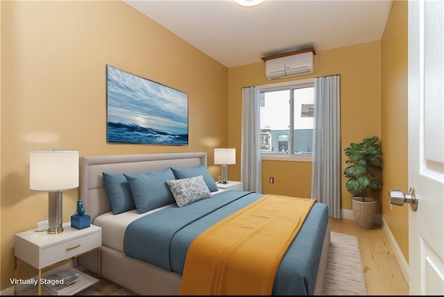 bedroom with baseboards, a wall unit AC, and wood finished floors