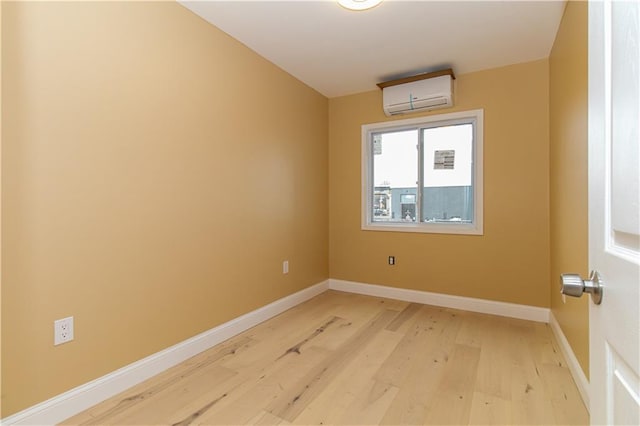 empty room featuring baseboards, a wall mounted AC, and light wood-style floors