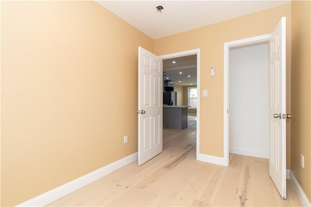 interior space featuring refrigerator, light wood-type flooring, and baseboards