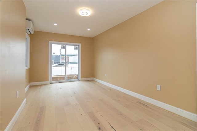 empty room featuring an AC wall unit, recessed lighting, baseboards, and light wood finished floors